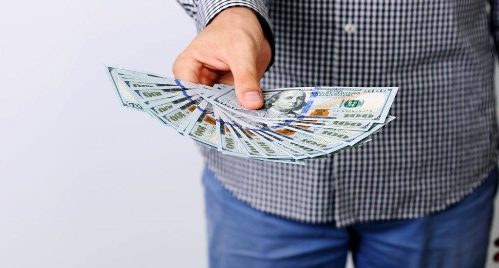 A man holding $100 bills