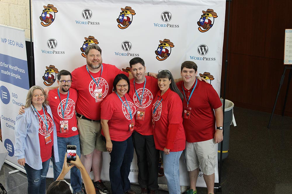 Organizers of WordCamp DFW psoing for a photo in front of a step and repeat