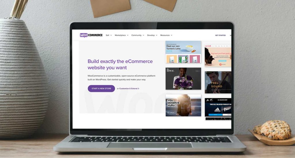 Screenshot of the WooCommerce homepage on a macbook pro sitting on a wooden table in front of a grey wall