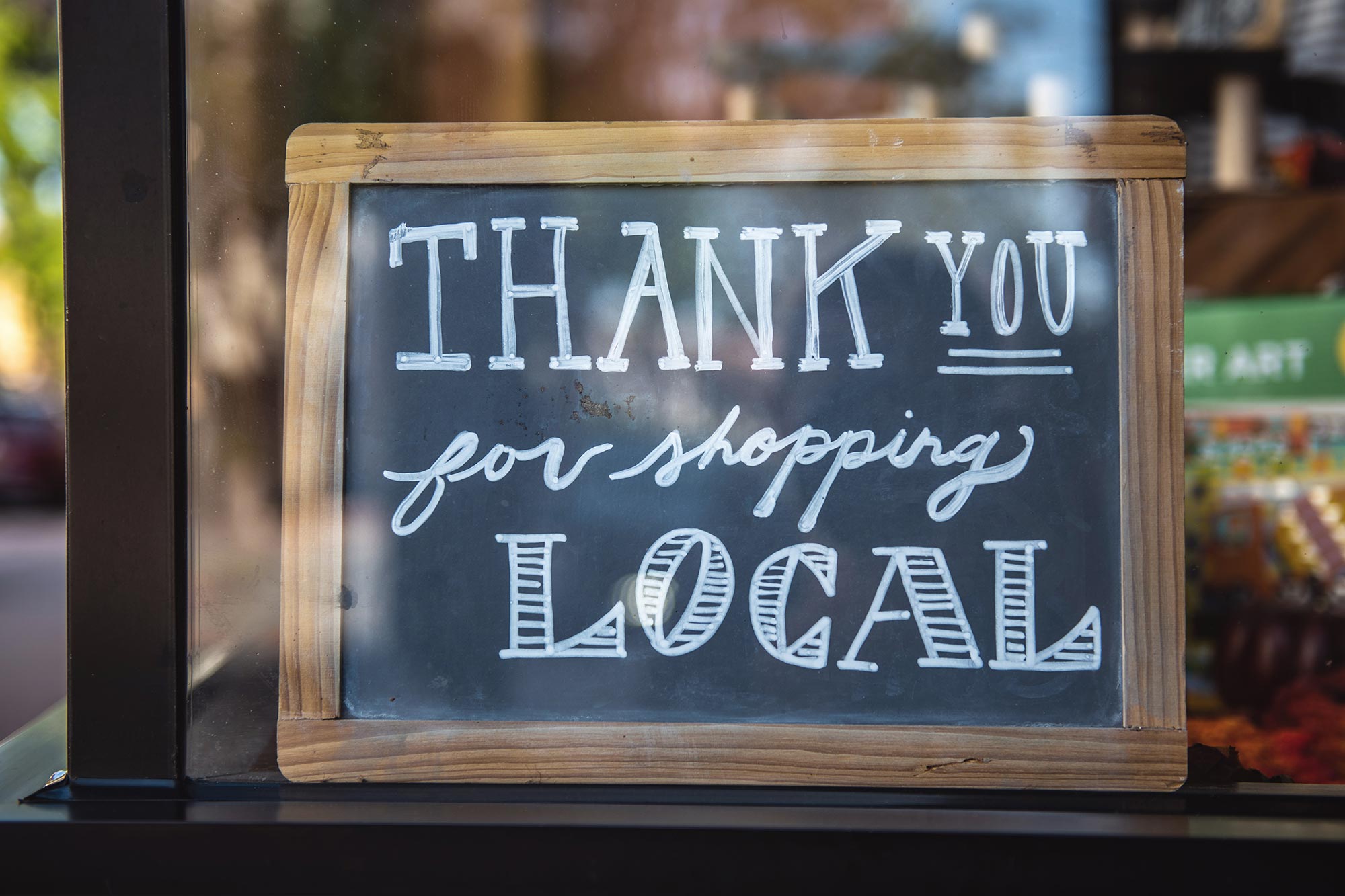 Photo of a sign in a small business window that reads "Thank You for shopping Local"