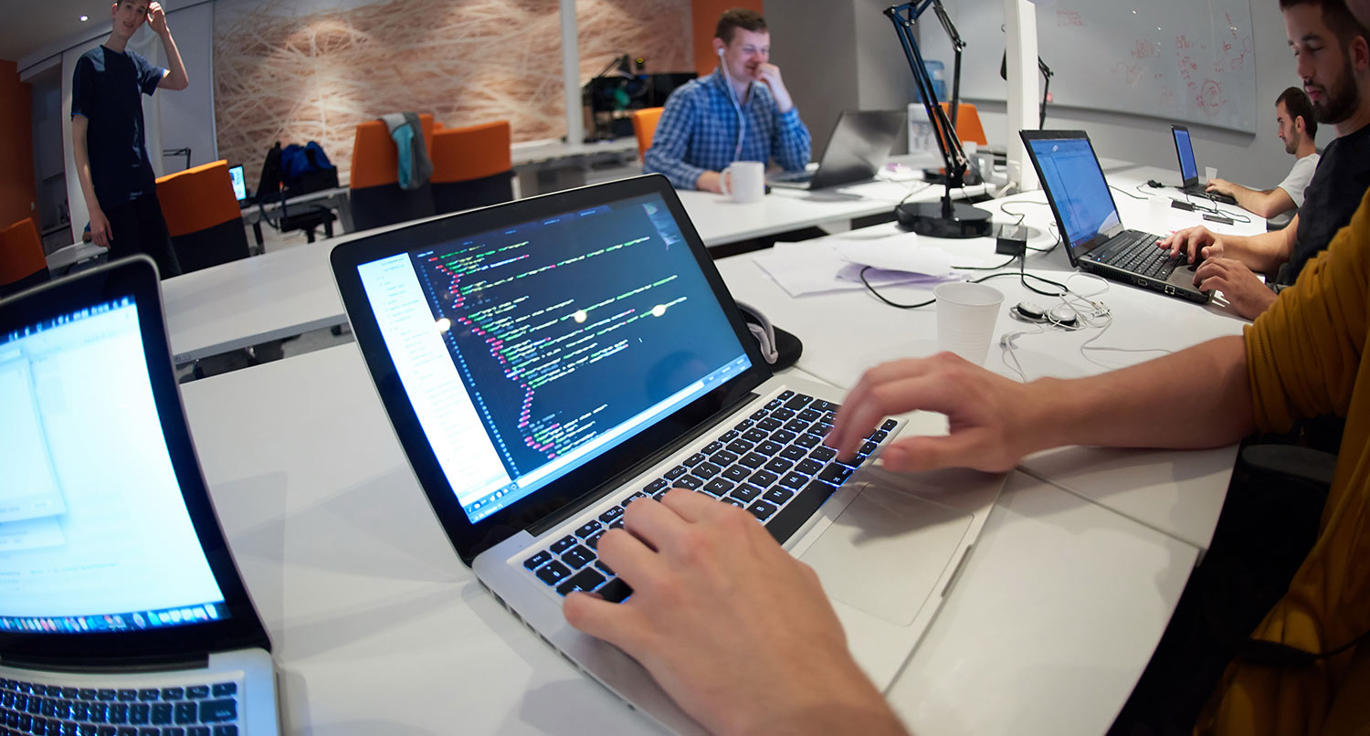 A person typing on a laptop in an open office