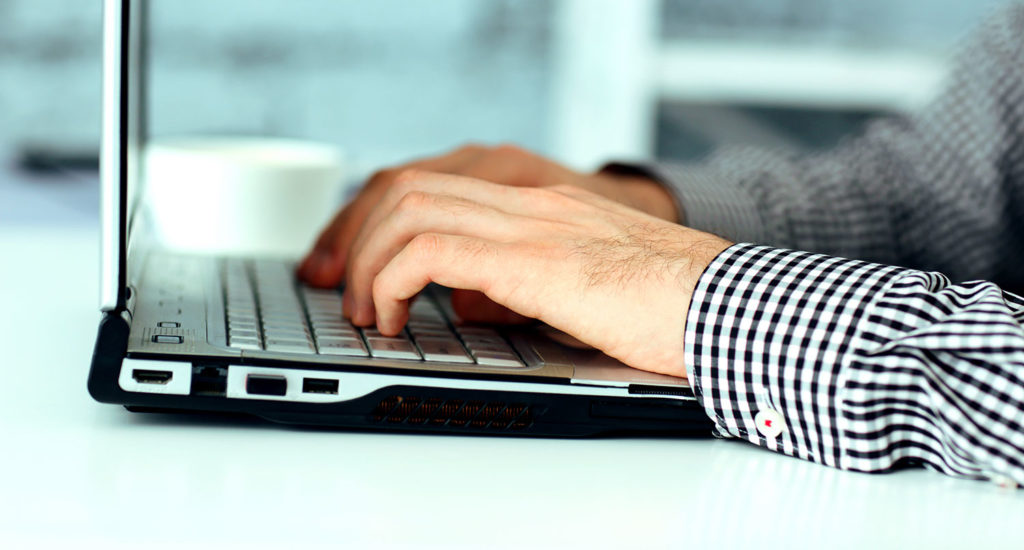 man typing on a laptop to blog