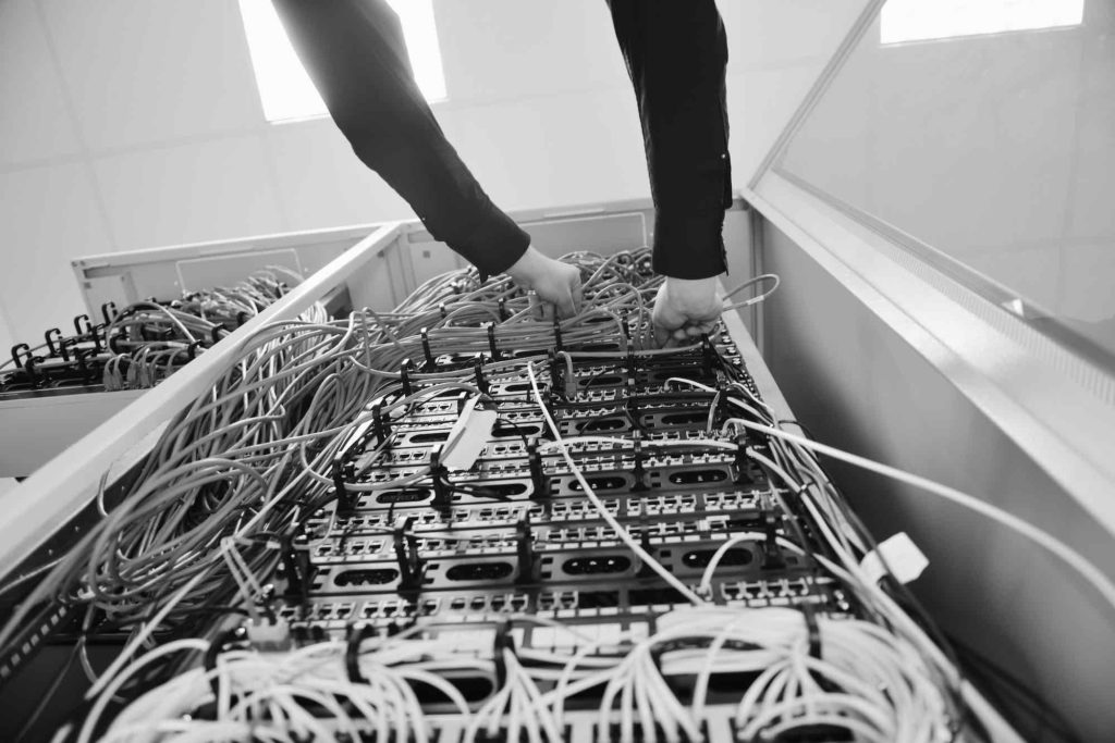 a person pulling on wires from a server stack