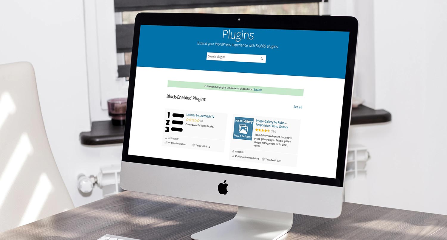 WordPress.org plugins page on an iMac on a wooden desk