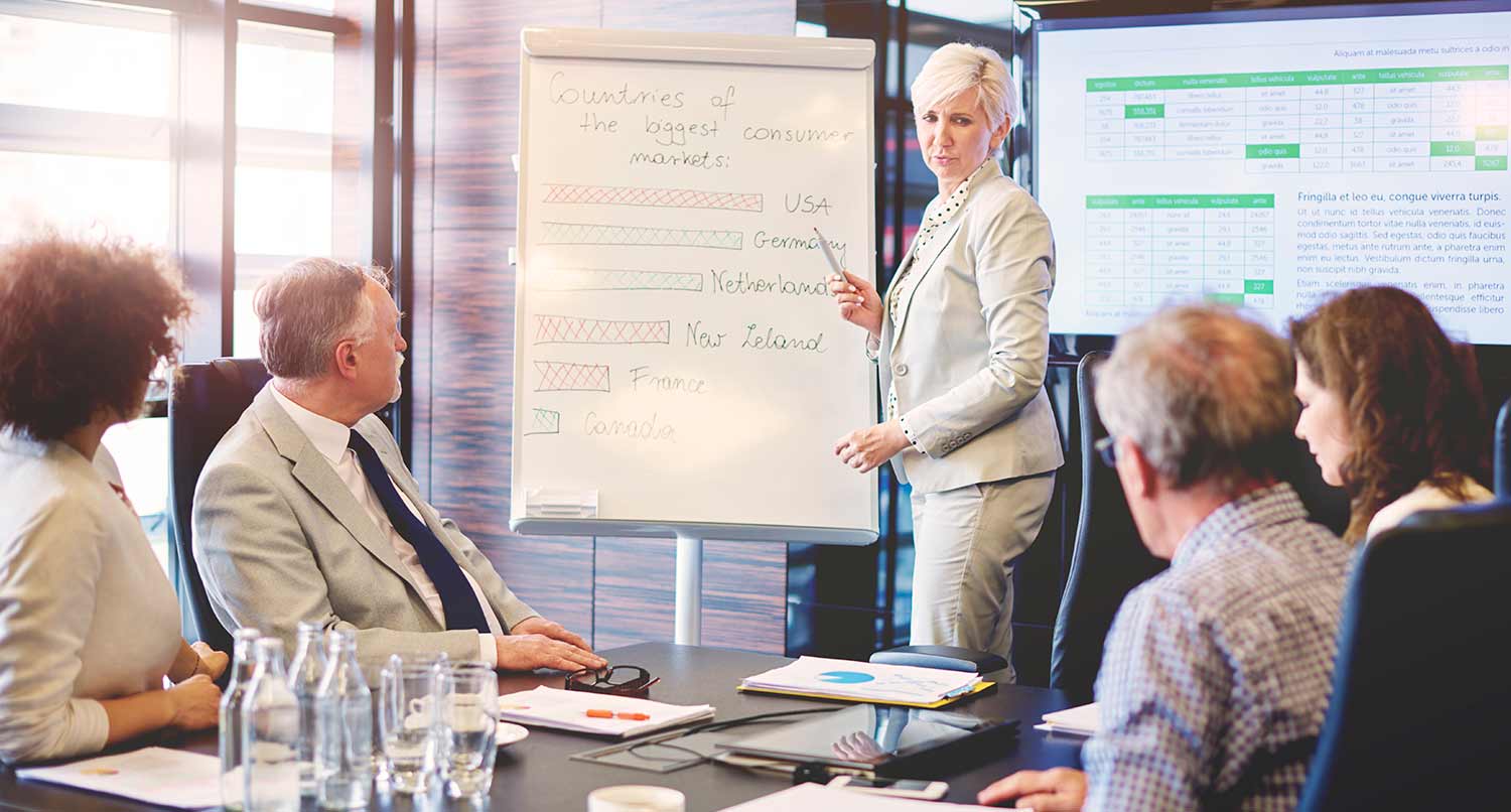 Woman standing in front of a notepad on a an easel in a business meeting