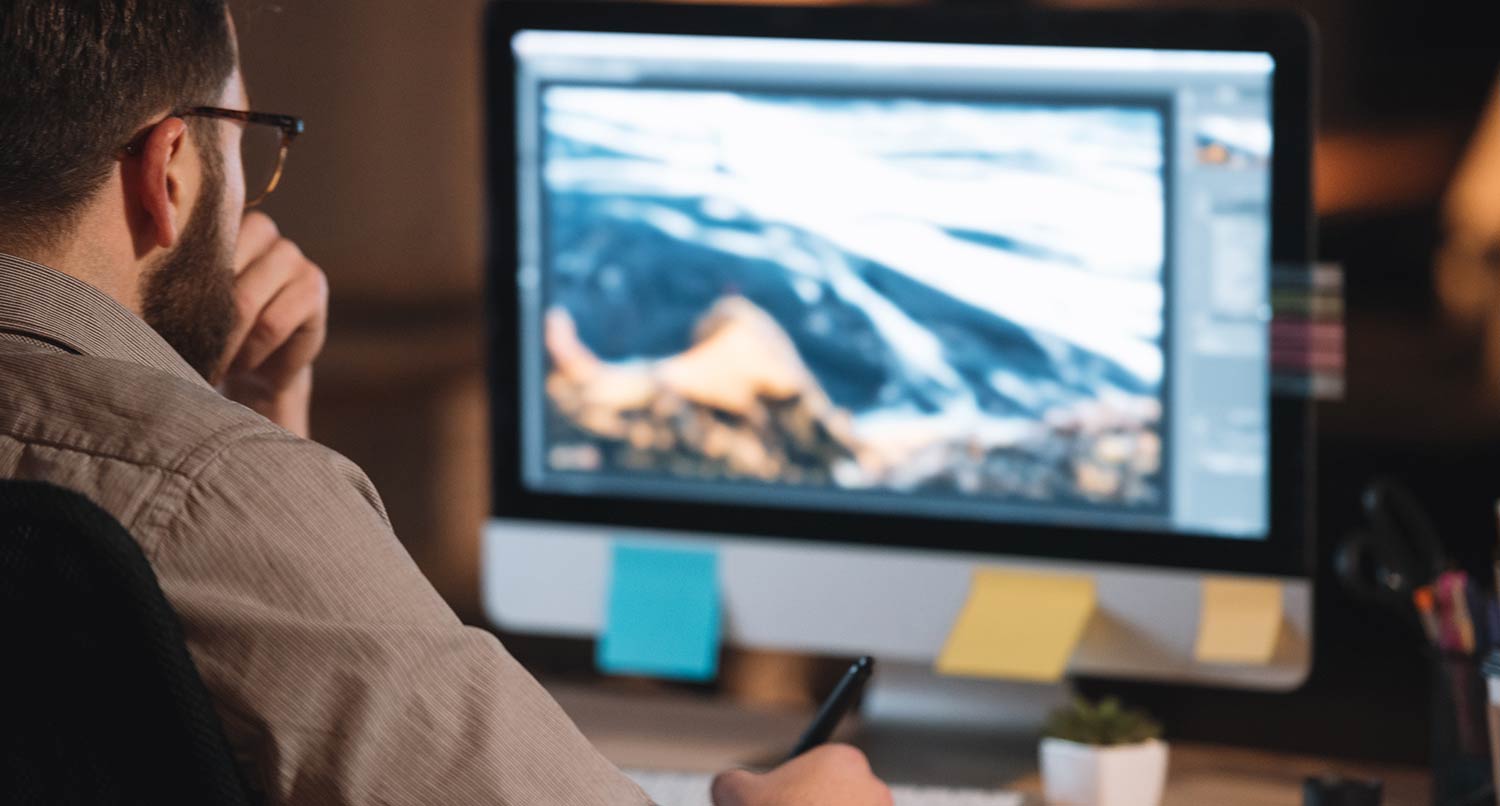 man working on an image in photoshop on an iMac computer