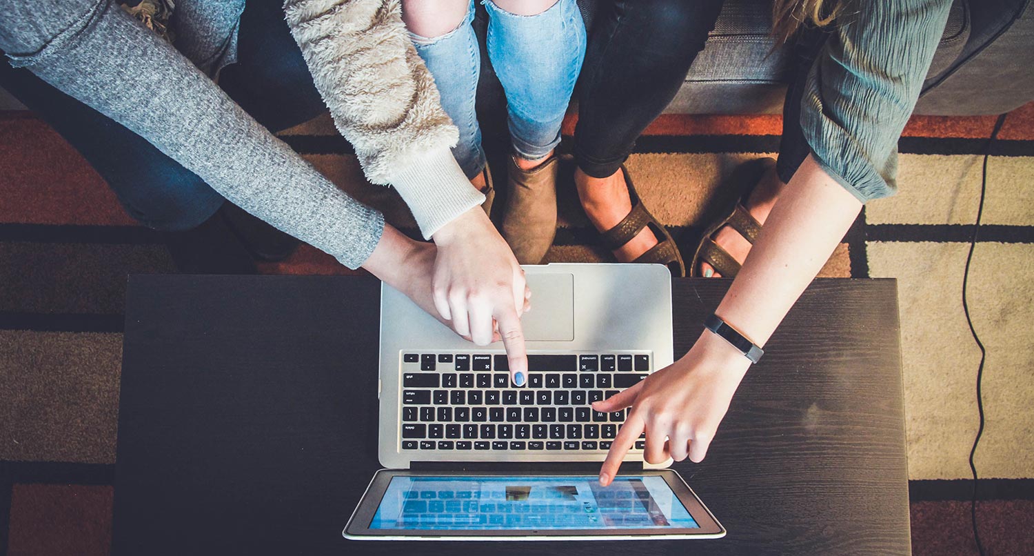 three people sitting on a couch working on a laptop on a coffee table