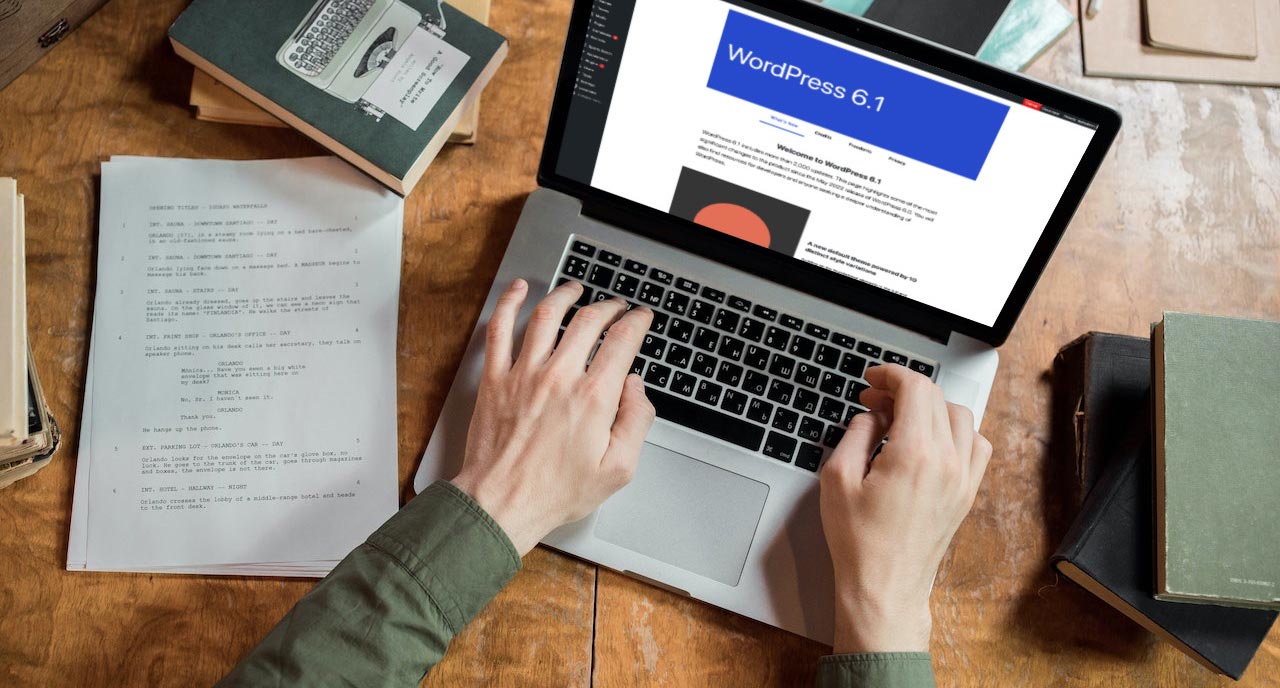 A laptop sitting on a wooden desk with books around it showing the WordPress 6.1 about page