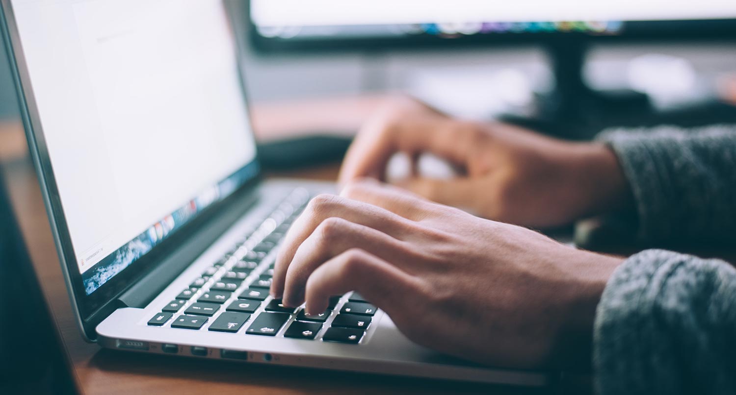 A person's hands typing on a MacBook pro laptop