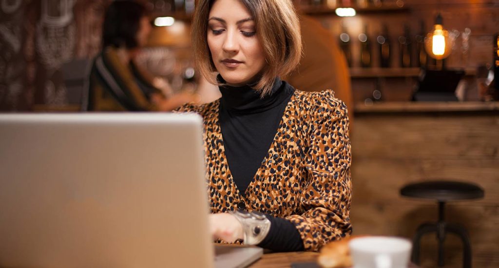 woman typing on a laptop inside a coffee shop