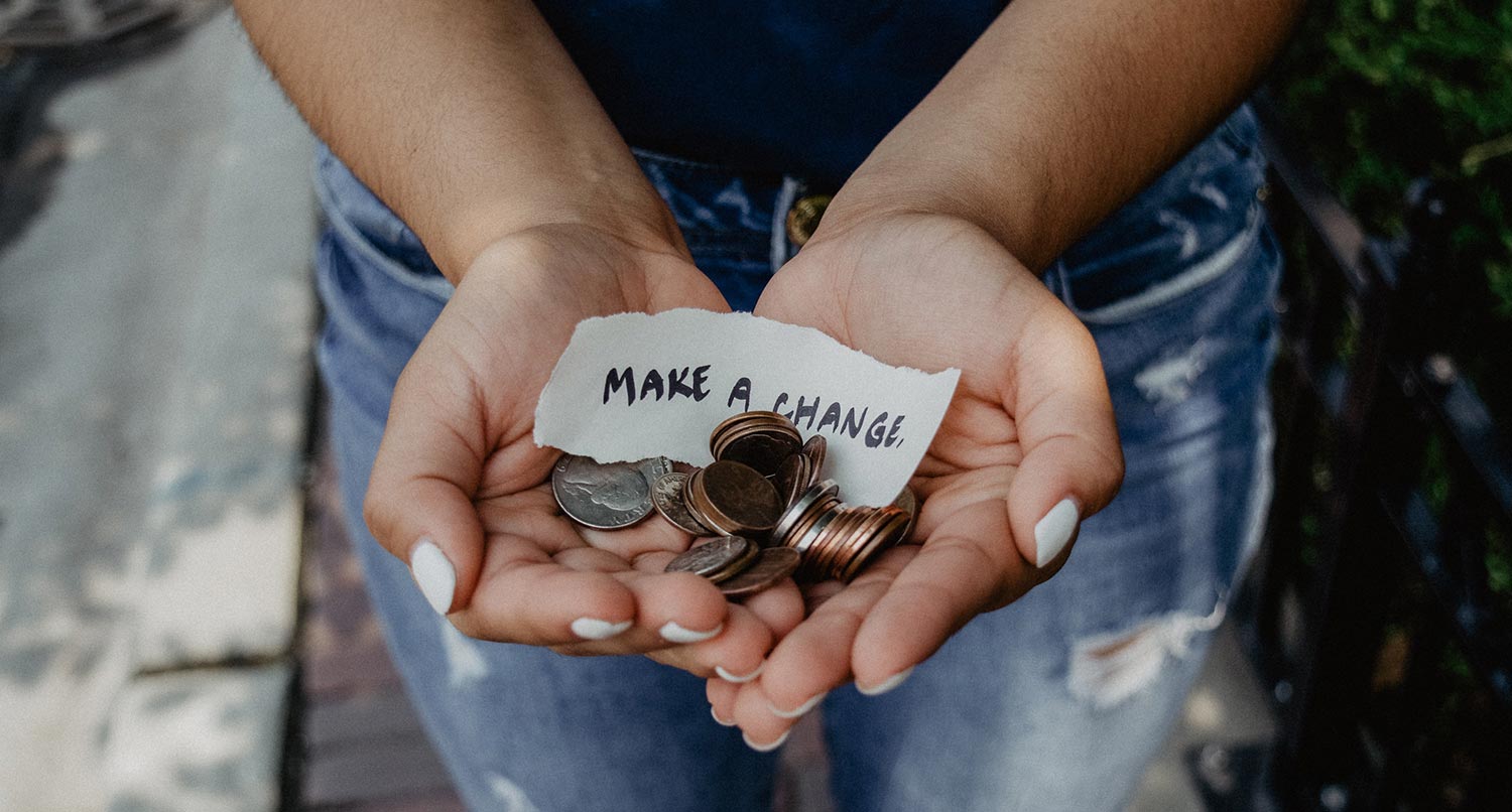 A person holding change and a piece of paper that says "Make a Change"