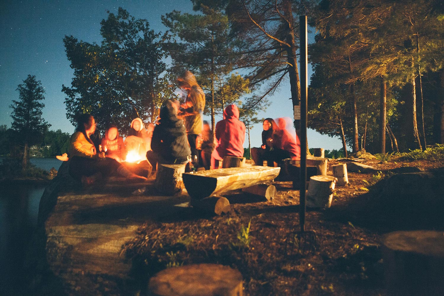a group of people sitting around a campfire at dusk