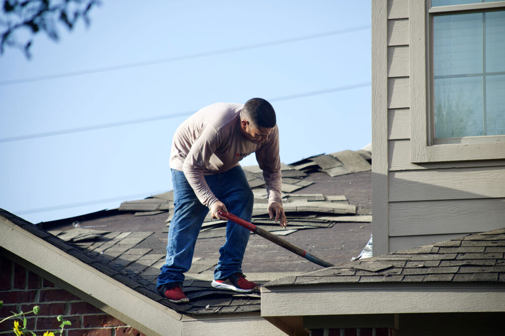 a man on a roof working on applying a new roof